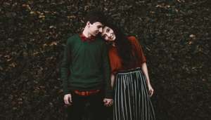 Young cute couple leaning in by hedge
