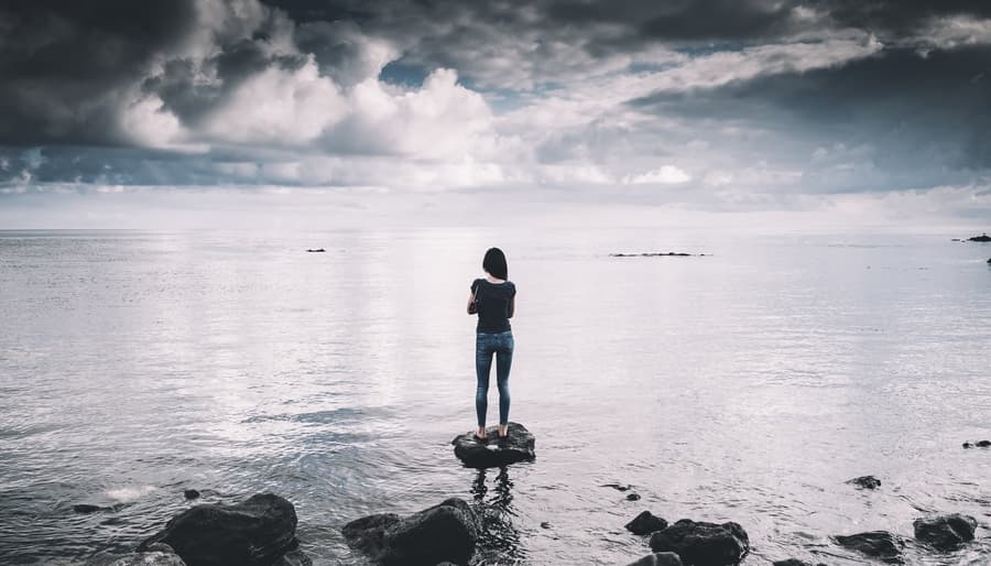 Woman Standing on Empty Beach looking at Horizon