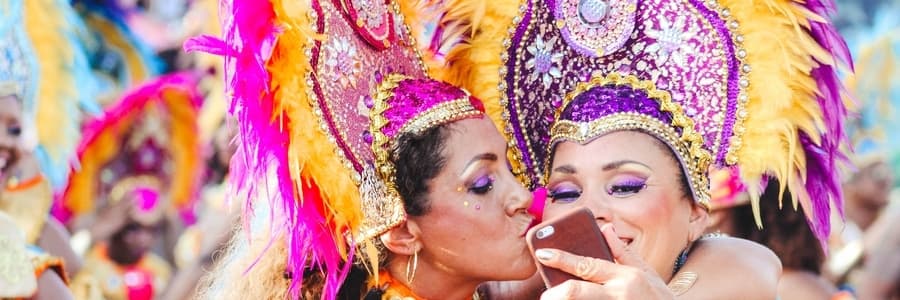 Women dressed up for Carnival embracing & taking photo