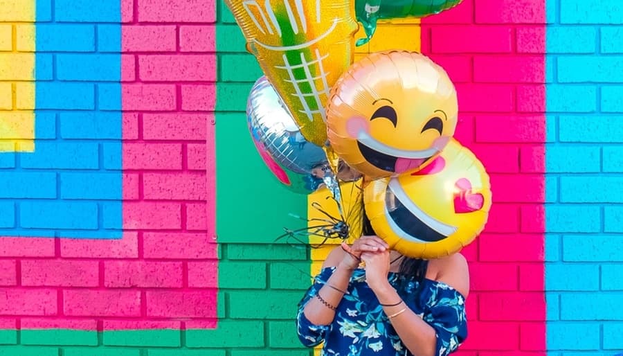 Woman Holding Bright Smiley Face Balloons Leo