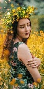 woman embracing herself in field of yellow flowers