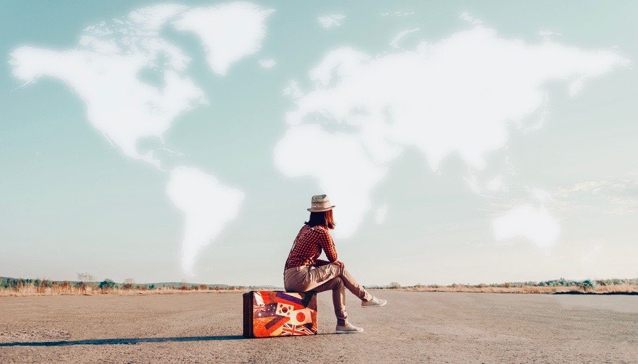 Women Traveler Sitting on case on Airfield, clouds forming map of the world