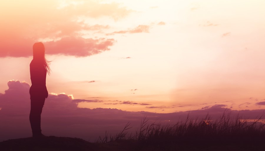 Woman Standing on Clifftop by Beautiful Red Sunset