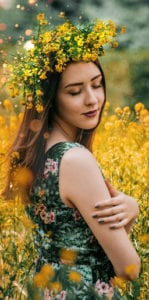 woman embracing herself in field of yellow flowers