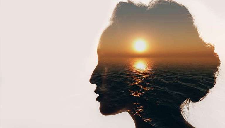 Dramatic image of a womens facial silhouette featuring a sunset over water