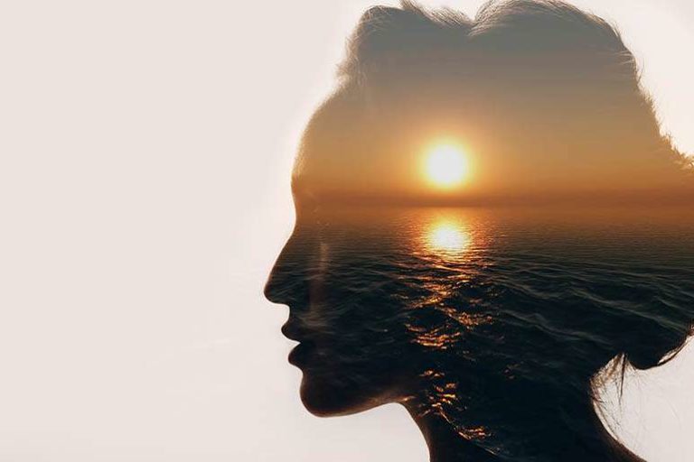 Dramatic image of a womens facial silhouette featuring a sunset over water